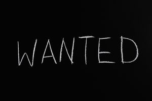 Black chalkboard with 'Wanted' written in white chalk, ideal for hiring or job concept visuals.